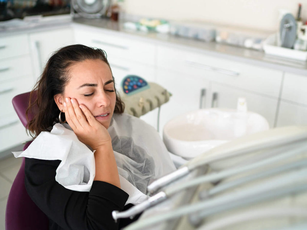 woman holding her jaw in pain