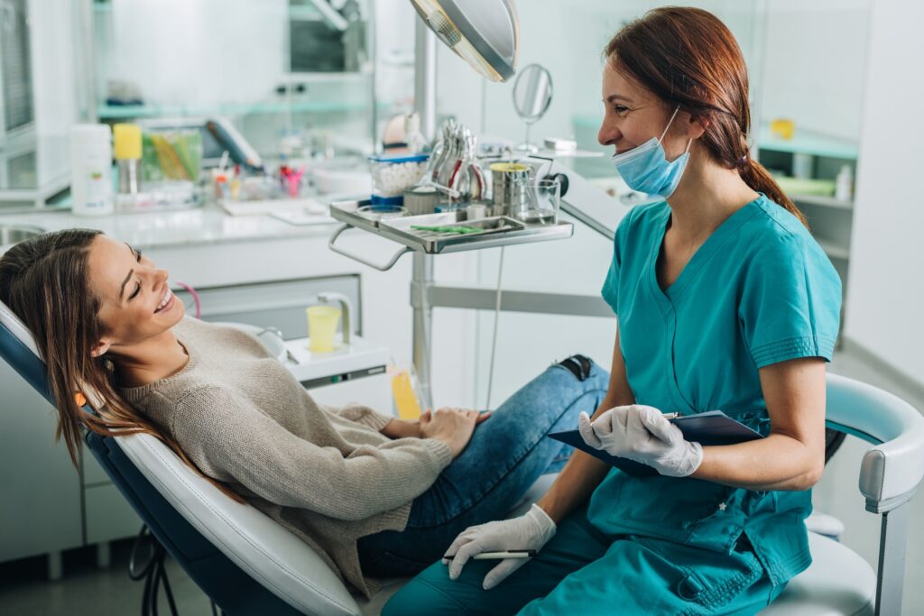 Dental assistant discussing dental services with patient that is sitting in exam chair