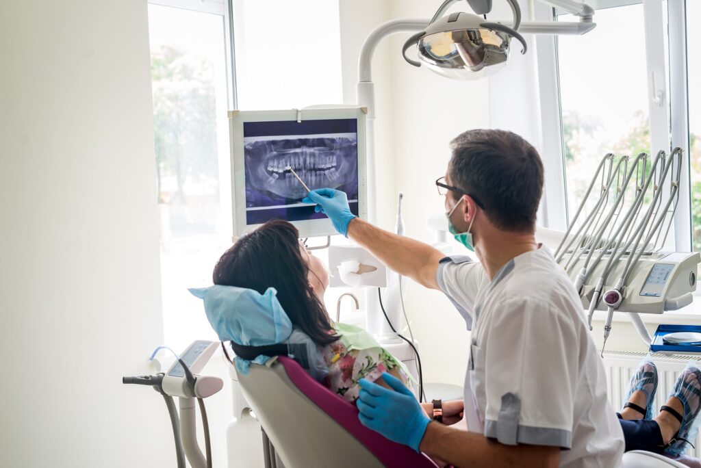 doctor explaining dental issues to patient by pointing to digital xray
