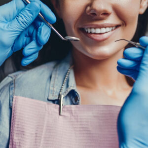 dentist holding dental tools in front of a smiling patient